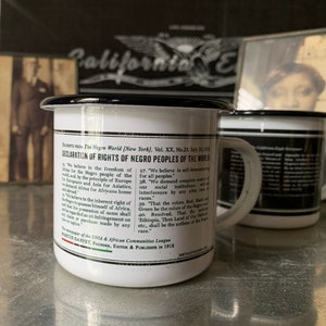 Peut inclure: Une tasse en &eacute;mail blanc avec un bord et une poign&eacute;e noirs. La tasse pr&eacute;sente une impression noir et blanc du texte "D&eacute;claration des droits des peuples noirs du monde". Le texte comprend les mots "Nous croyons en la libert&eacute; du monde pour le peuple noir" et "Nous exigeons le contr&ocirc;le total de toutes les institutions sociales sans ing&eacute;rence de la part de aucune race."