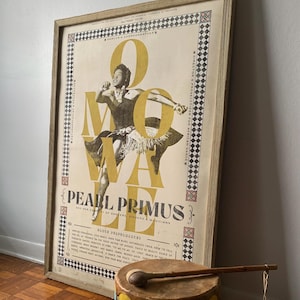 May include: A vintage poster advertising a performance by Pearl Primus and her company of dancers, singers, and musicians. The poster features a black and white image of Pearl Primus in a dance pose, with the word "OMOVA" spelled out in large, yellow letters. The poster is framed in a light wood frame.