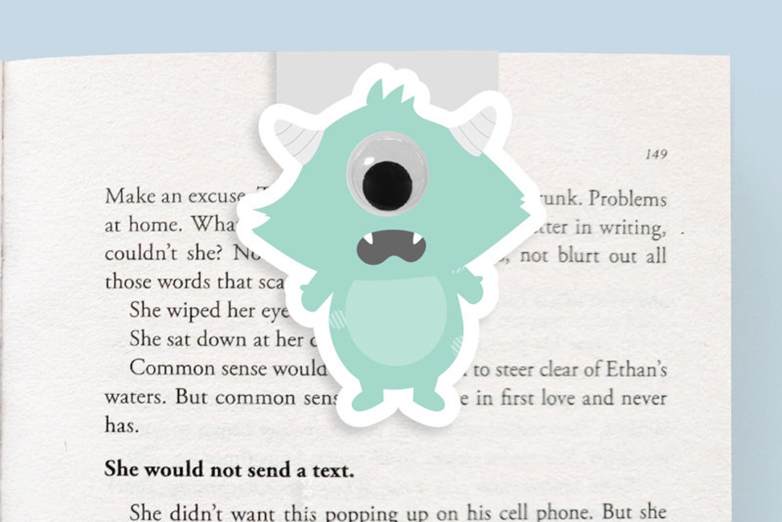 Image of a book with a green magnetic monster bookmark with one eye and two horns