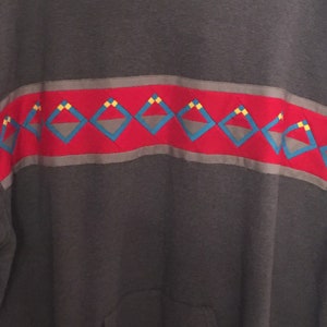 May include: A dark gray hooded sweatshirt with a red, gray, blue, and yellow geometric pattern across the chest.