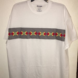 May include: White t-shirt with a grey band across the chest. The band has a pattern of red, yellow, and blue squares. The shirt has a Gildan label with the text "Gildan" and "Softstyle" printed on it.