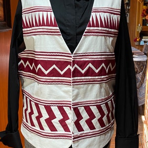 May include: A white vest with a burgundy geometric pattern. The vest has a pointed collar and a button closure.