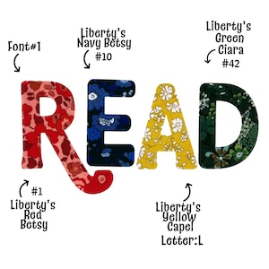 Könnte beinhalten: Das Wort READ, buchstabiert in vier Stoffbuchstaben. Das R ist rotes Blumenmuster Liberty's Red Betsy #1, das E ist marineblaues Blumenmuster Liberty's Navy Betsy #10, das A ist gelbes Blumenmuster Liberty's Yellow Capel #L, das D ist grünes Blumenmuster Liberty's Green Ciara #42.
