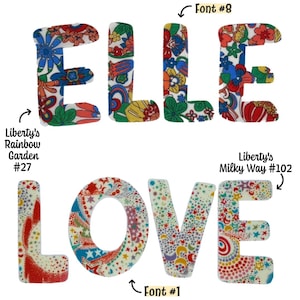 May include: Two rows of fabric letters. The top row spells ELLE in a floral pattern labeled Liberty's Rainbow Garden #27 and Font #8. The bottom row spells LOVE in a celestial pattern labeled Liberty's Milky Way #102 and Font #1.