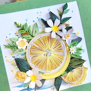 Könnte beinhalten: Ein handgefertigtes Papier-Quilling-Kunstwerk mit einer aufgeschnittenen Zitrone mit gelben und weißen Details. Die Zitrone ist von weißen Blüten, grünen Blättern und blauen Akzenten umgeben, alles auf einem weißen Hintergrund mit einem grünen Rand.