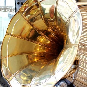 Puede incluir: Un gran cuerno de gram&oacute;fono vintage de color dorado con una abertura acampanada y una superficie lisa y brillante.