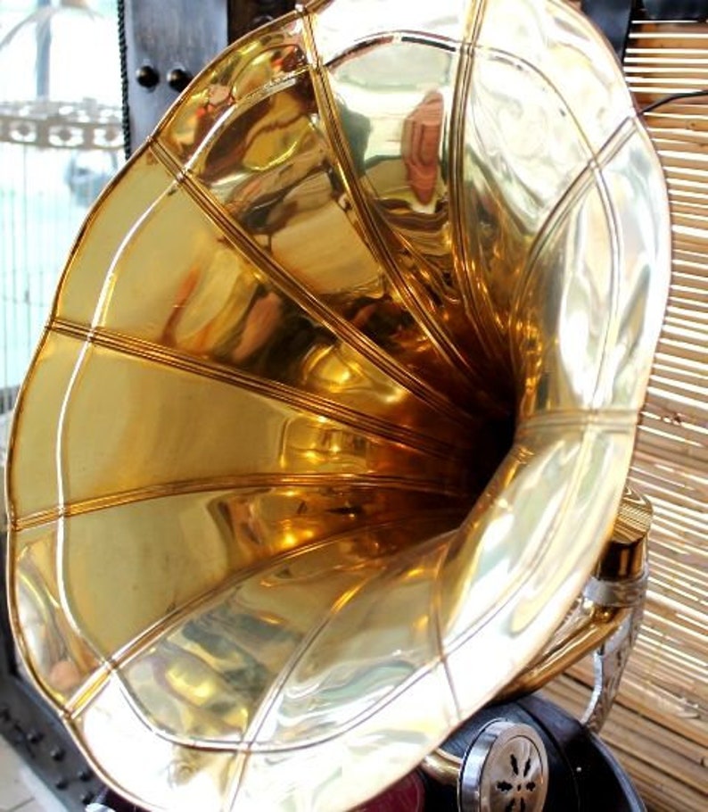 Puede incluir: Un gran cuerno de gram&oacute;fono vintage de color dorado con una abertura acampanada y una superficie lisa y brillante.