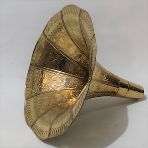 Puede incluir: Un cuerno de gram&oacute;fono de metal dorado con un patr&oacute;n floral decorativo. El cuerno es ancho en la abertura y se estrecha a un di&aacute;metro m&aacute;s peque&ntilde;o en el extremo.