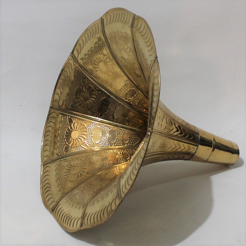 Puede incluir: Un cuerno de gram&oacute;fono de metal dorado con un patr&oacute;n floral decorativo. El cuerno es ancho en la abertura y se estrecha a un di&aacute;metro m&aacute;s peque&ntilde;o en el extremo.