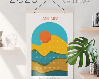 May include: A 2025 calendar with a minimalist design featuring a yellow, orange, and blue sunset over a series of green and yellow waves. The month of January is displayed with the days of the week labeled S, M, T, W, T, F, S. The calendar is titled "12-month calendar" and is credited to "Chelsey Design."