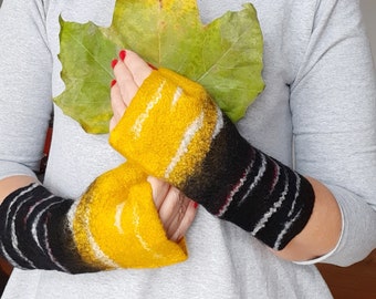 Può includere: Un paio di guanti senza dita con una consistenza infeltrita e una sfumatura di colore che passa dal giallo brillante al nero. I guanti sono arricchiti da sottili linee orizzontali in fibra bianca e rossa che avvolgono il polso e l'avambraccio.