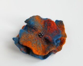 May include: A blue and orange felt flower brooch with black beads in the center.