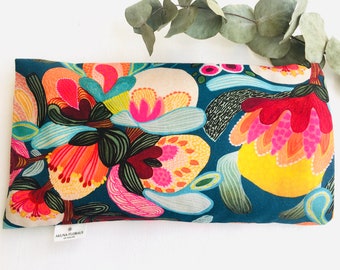 May include: A teal blue fabric eye pillow with a colorful floral print. The print features bright pink, yellow, orange, and red flowers with green leaves. The pillow has a label that reads "Akuna Florals".