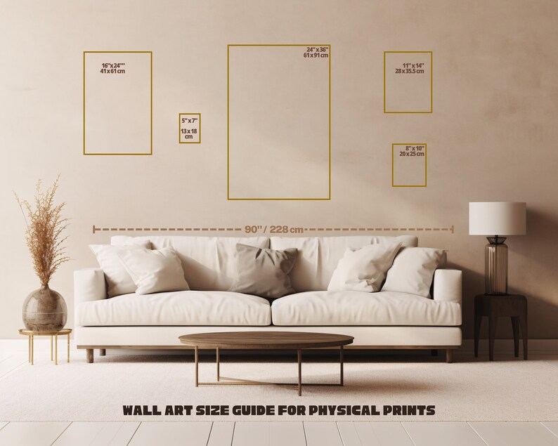 May include: A wall art size guide for physical prints with a white couch and a table in front of it. The guide shows different sizes of prints in inches and centimeters. The wall is beige and the floor is light brown.