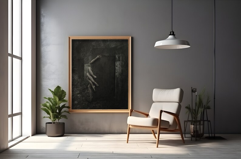 May include: A black and white photograph of a person reaching out from a dark, shadowy space. The photograph is framed in a wooden frame and hanging on a gray wall.