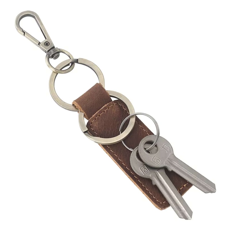 May include: A brown leather key chain with a metal ring and two keys attached. The key chain has a metal clip.