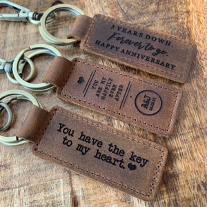 May include: Three leather keychains with engraved messages. The first keychain says "3 Years Down. Forever to go. Happy Anniversary". The second keychain says "You are my happily ever after". The third keychain says "You have the key to my heart."