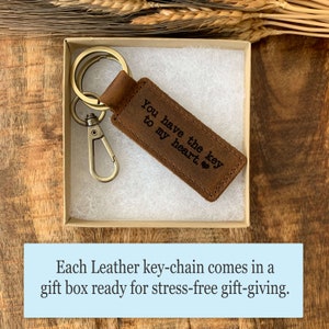 May include: A brown leather keychain with a silver key ring and a small brown leather tag that says "You have the key to my heart." The keychain is in a small brown gift box.
