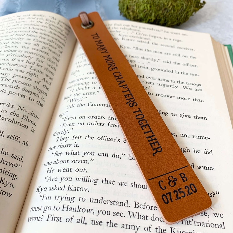 Peut inclure: Un marque-page en cuir marron avec le texte "To Many More Chapters Together" et "C&B 07.25.20" en lettres noires. Le marque-page est un excellent cadeau pour les bibliophiles.