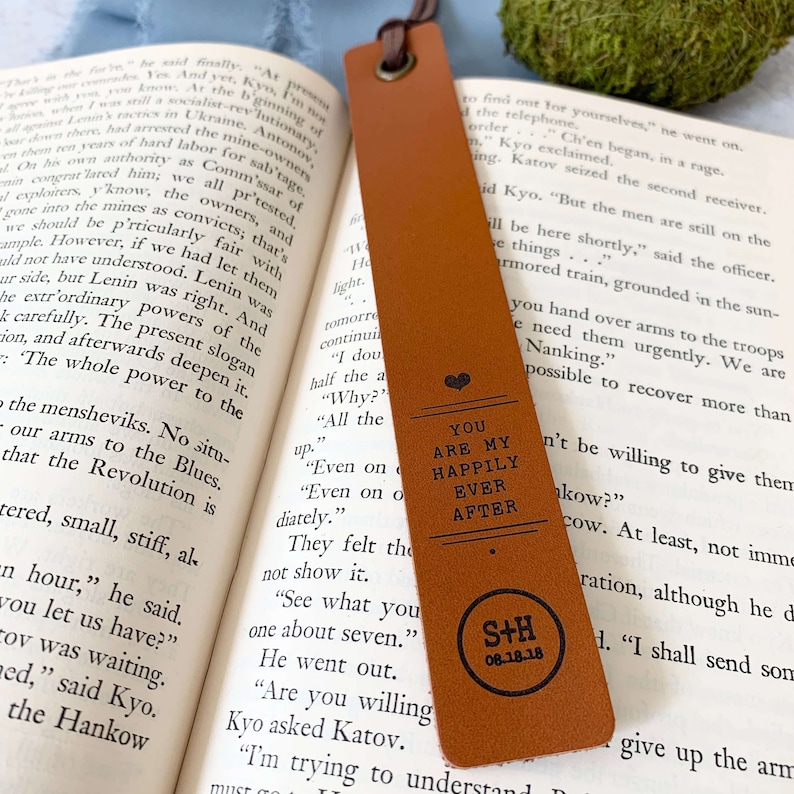 Peut inclure: Un marque-page en cuir marron avec un c&oelig;ur et le texte "You are my happily ever after" et les initiales "S+H" avec la date "08.18.18".