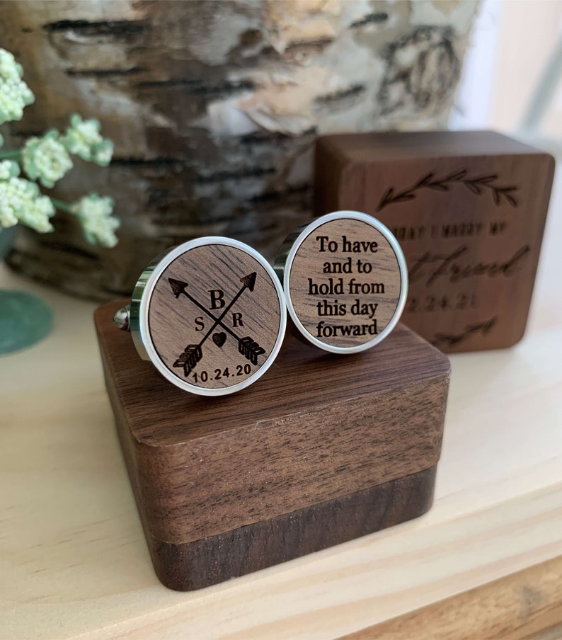 May include: A pair of wooden cufflinks in a wooden box. One cufflink has the text "To have and to hold from this day forward" and the other cufflink has the initials "S & R" with arrows and a heart and the date "10.24.20".