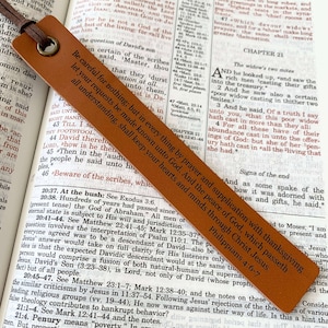 May include: A brown leather bookmark with a quote from Philippians 4:6-7, "Be careful for nothing; but in every thing by prayer and supplication with thanksgiving let your requests be made known unto God. And the peace of God, which passeth all understanding, shall keep your hearts and minds through Christ Jesus."