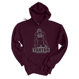 May include: Burgundy hooded sweatshirt with a gray graphic of a football player with the number 92 and the text "GALVAN" on the back. The text "TARTAR FOOTBALL PRIDE" is printed below the player.