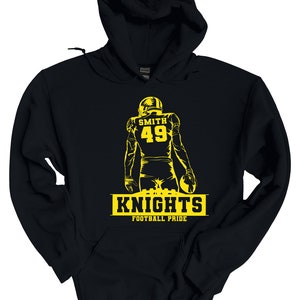 May include: Black hooded sweatshirt with a yellow silhouette of a football player wearing a helmet and jersey with the number 49 and the name "SMITH" on the back. The text "KNIGHTS FOOTBALL PRIDE" is printed below the player.