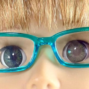 May include: A pair of teal blue plastic framed glasses with clear lenses.