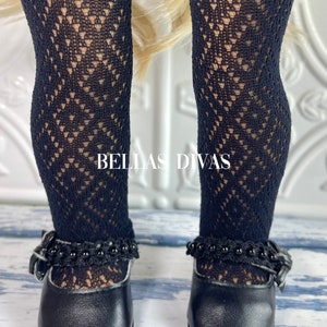 May include: Black lace tights with a diamond pattern and black leather shoes with a buckle and beaded trim.  The shoes have a rounded toe and a low heel.