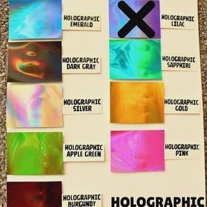 May include: A display of holographic color samples, including emerald, dark gray, silver, apple green, and burgundy. Other colors include lilac, sapphire, gold, and pink. The word "HOLOGRAPHIC" is printed on the bottom right.