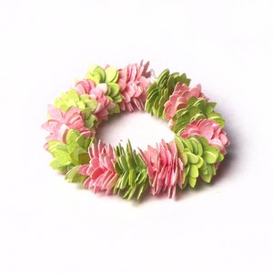 Könnte beinhalten: Eine Girlande aus rosa und grünen Papierblumen.