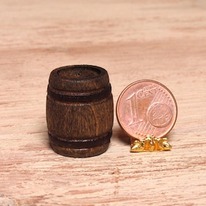 Könnte beinhalten: Ein kleines Holzfass mit dunkelbrauner Oberfläche und zwei Metallbändern. Das Fass befindet sich neben einer 1-Cent-Euro-Münze zur Größenbestimmung.