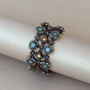 K&ouml;nnte beinhalten: Ein Armband mit Perlen in geometrischem Design mit blauen und goldenen Perlen.