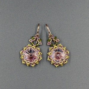 May include: A pair of dangle earrings with a pink and green flower design. The earrings are made with small beads and have a gold-tone finish.