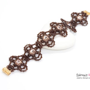 May include: A brown beaded bracelet with a delicate, intricate design. The bracelet features small, clear crystals and gold-toned clasps.