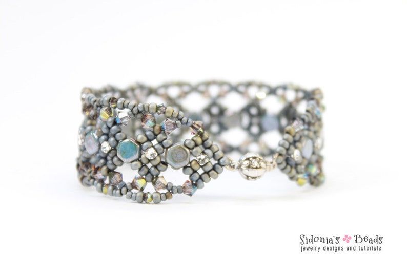 May include: A silver and grey beaded bracelet with a woven design and iridescent accents. The bracelet is made with small seed beads and larger, faceted beads.