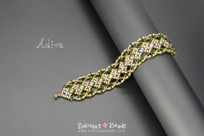 May include: A green and pink beaded bracelet with a floral design. The bracelet is made with small, iridescent beads and is on a grey background.