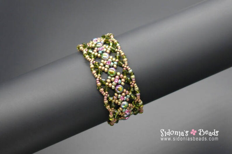 May include: A multi-strand beaded bracelet with a geometric pattern. The bracelet is made with green, gold, and pink beads.