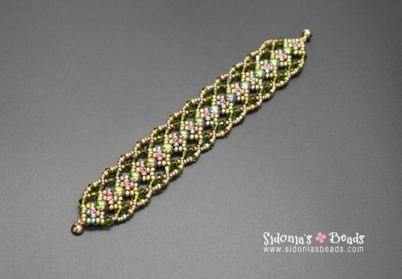 May include: A green and gold beaded bracelet with a geometric pattern. The bracelet is made with small seed beads and features a subtle iridescent sheen.