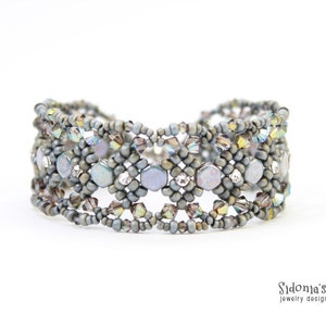 May include: A grey beaded bracelet with iridescent accents. The bracelet is made with small, round beads and features a geometric pattern.
