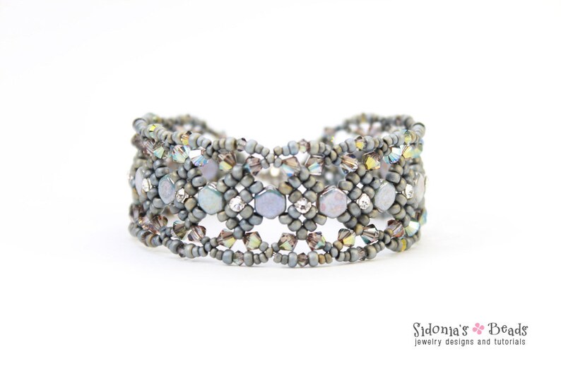 May include: A grey beaded bracelet with iridescent accents. The bracelet is made with small, round beads and features a geometric pattern.