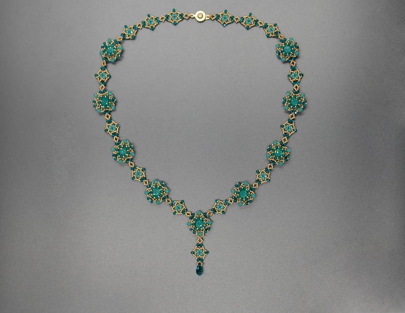 Pu&ograve; includere: Una collana color oro con motivi floreali di perline color teal. La collana ha una catena delicata e un pendente centrale. L'intricato lavoro di perline crea un gioiello bello e accattivante.