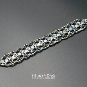 May include: A silver and grey beaded bracelet with a clasp fastening. The bracelet is made with small, round beads and has a geometric pattern.