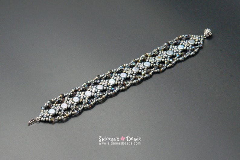 May include: A silver and grey beaded bracelet with a clasp fastening. The bracelet is made with small, round beads and has a geometric pattern.
