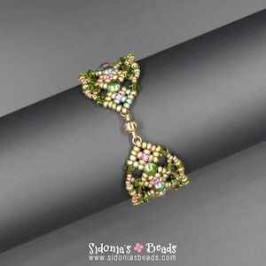 May include: A green, pink and gold beaded bracelet with a geometric design. The bracelet is made with seed beads and features a delicate, intricate pattern.