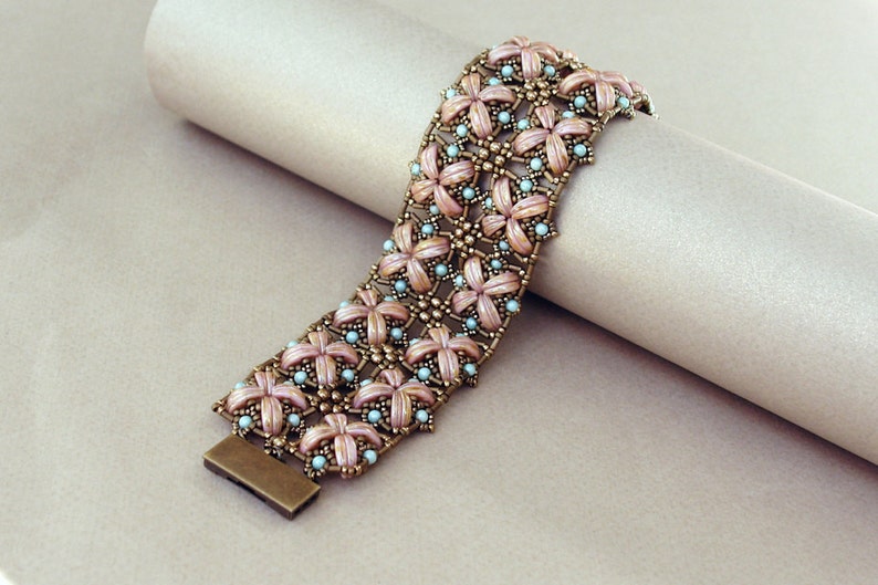 Pu&ograve; includere: Un braccialetto di perline rosa e blu con un design floreale. Il braccialetto &egrave; realizzato con piccole perline rotonde e ha una chiusura in metallo.