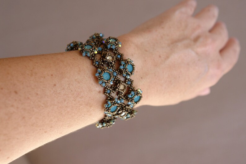 K&ouml;nnte beinhalten: Ein mehrreihiges Armband mit blauen und goldenen Perlen. Das Armband besteht aus kleinen, runden Perlen, die in einem Muster aufgereiht sind. Das Armband wird am Handgelenk getragen.