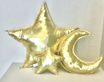 May include: Three gold-colored pillows shaped like a large star, a smaller star, and a crescent moon.
