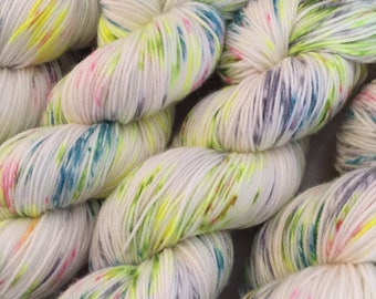 Puede incluir: Hilo blanco con motas de verde, azul, rosa y amarillo.